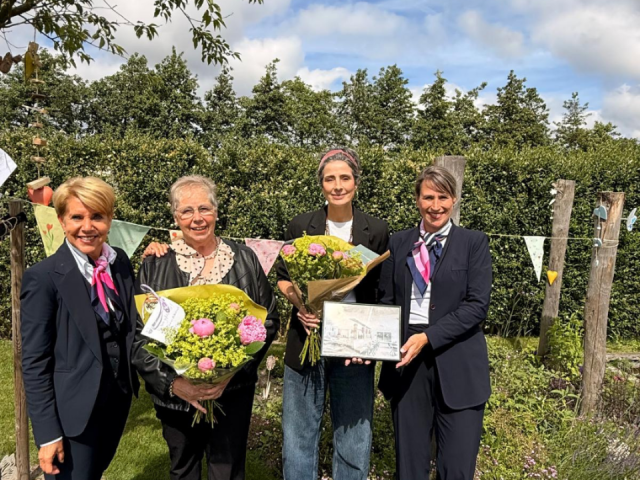 Twee winnaars van de fotowedstrijd met hun boeket en ingelijste winnende foto in de tuin.